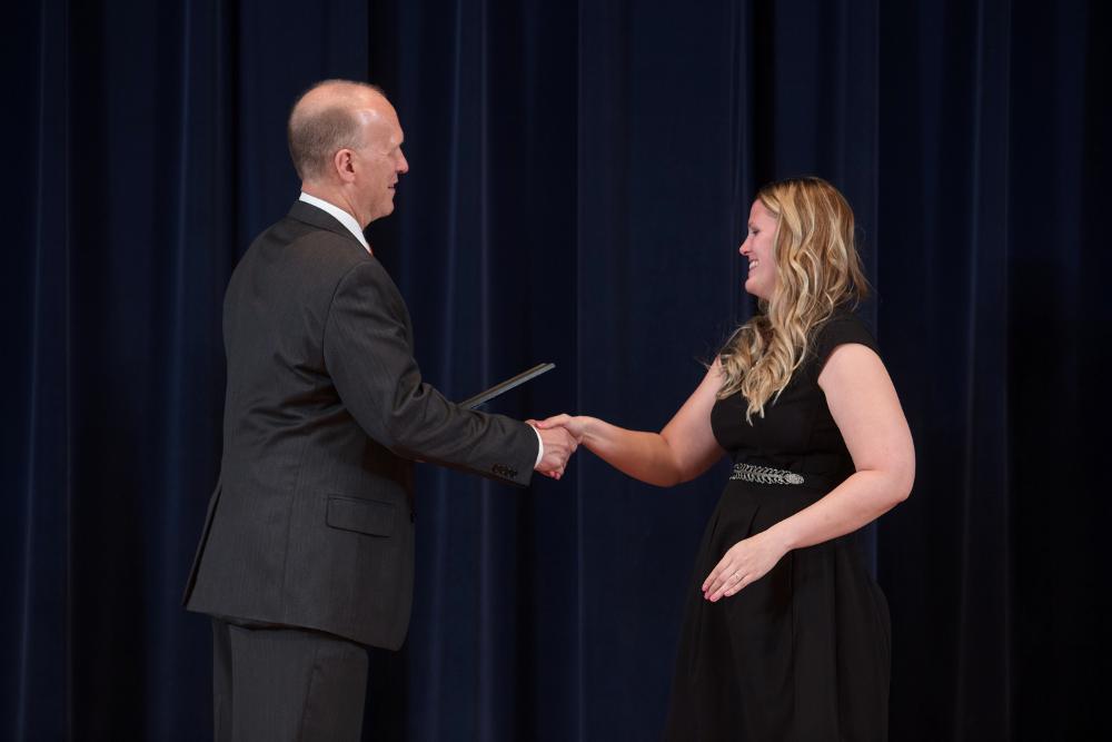 Doctor Potteiger shaking hands with an award recipient in a black dress